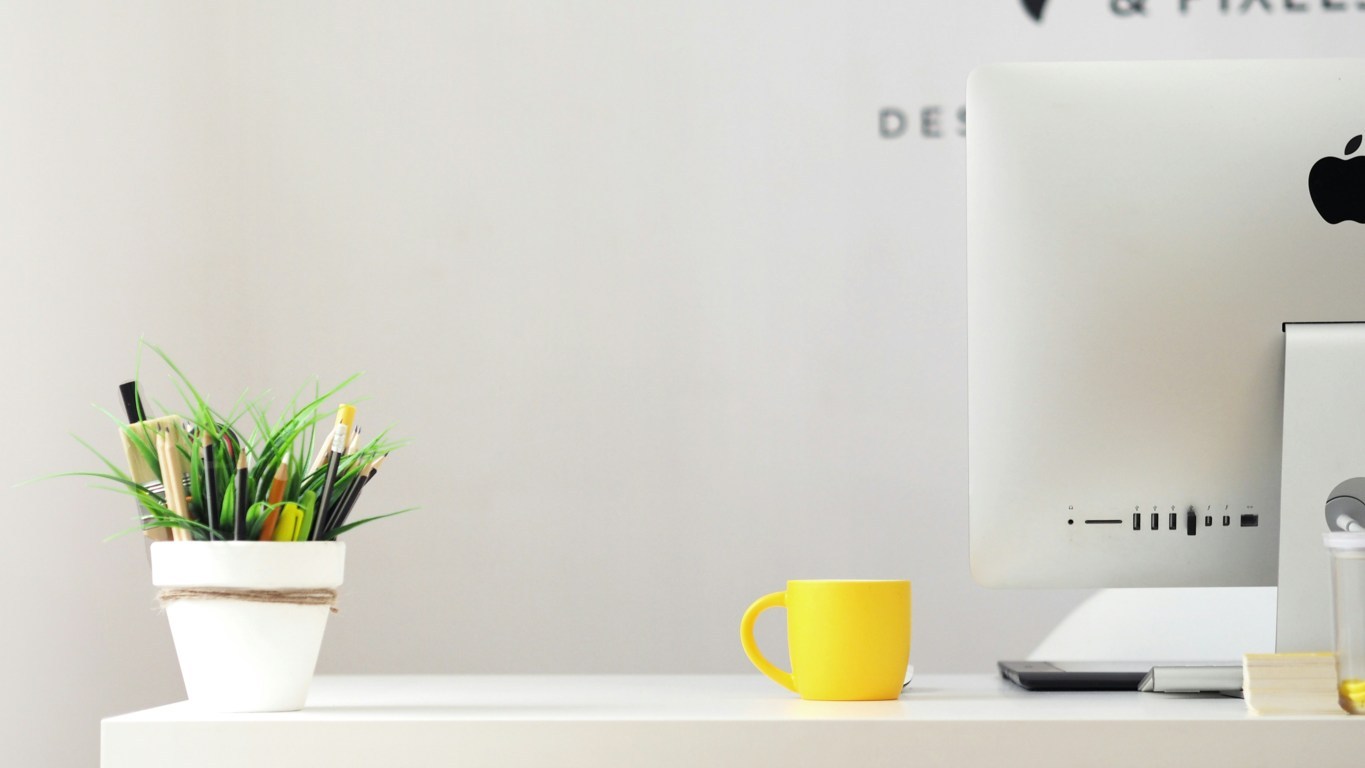 postazione di lavoro: scrivania con computer e tazza da caffè gialla